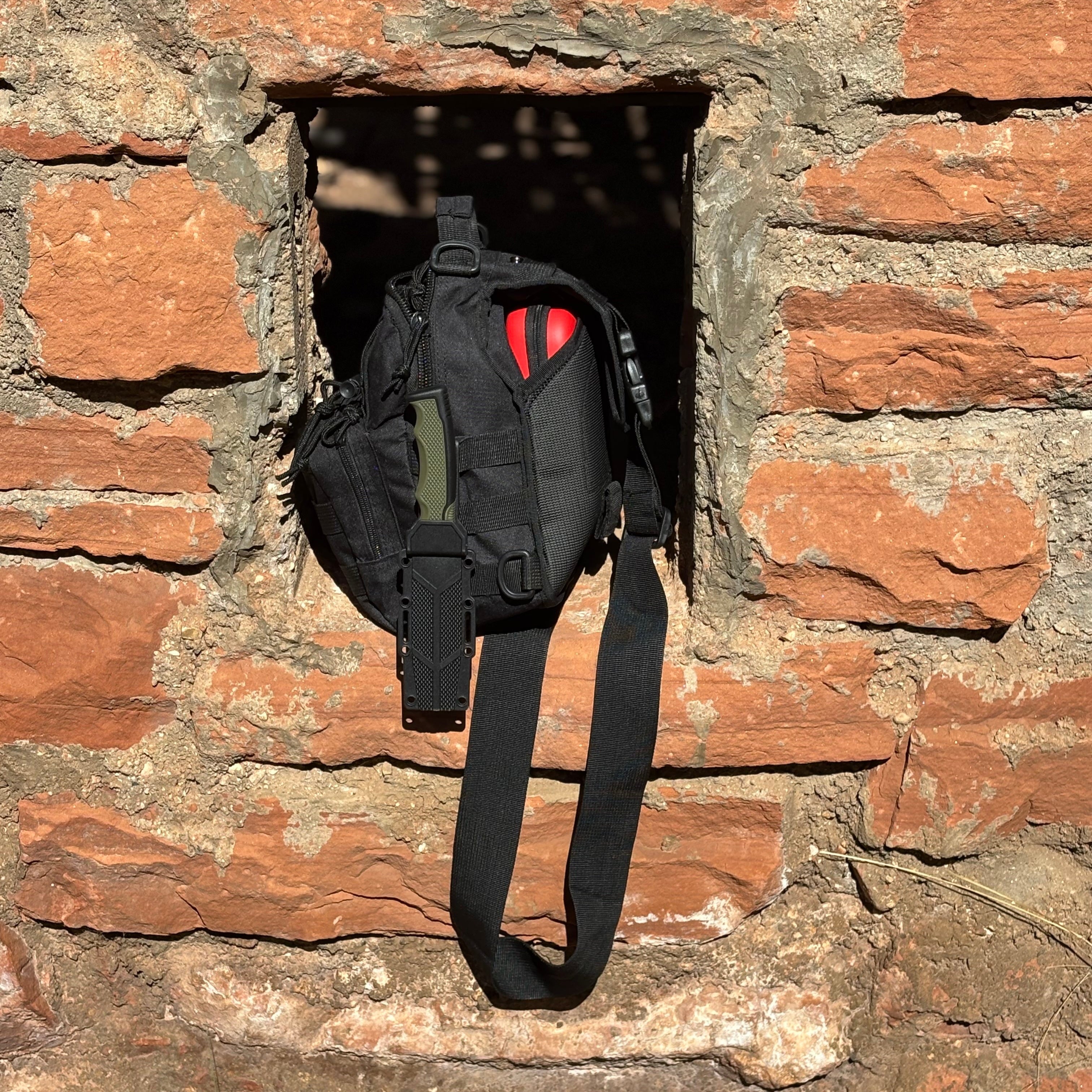 Black bag with a red heart symbol hanging from a stone wall.