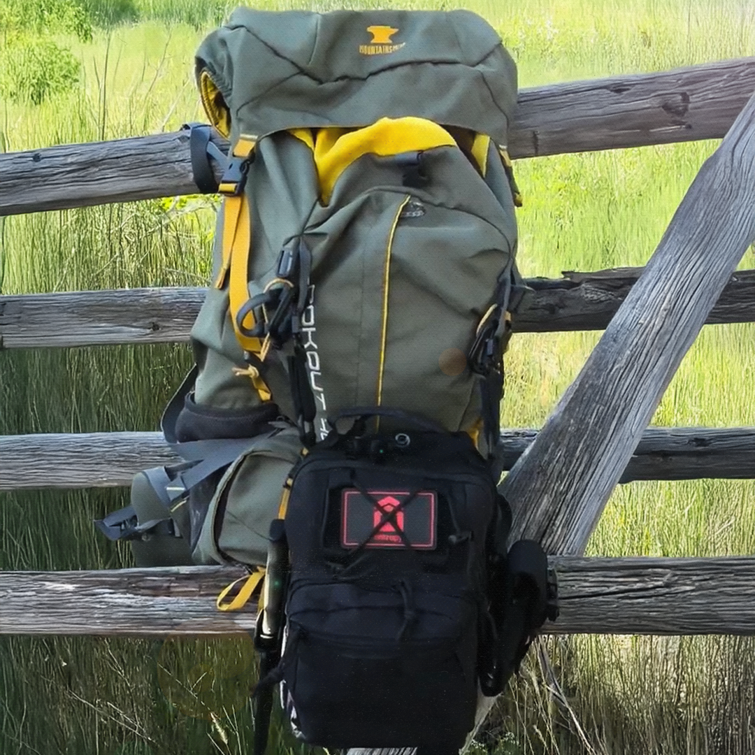 Backpack with visible branding on a wooden fence in a natural setting