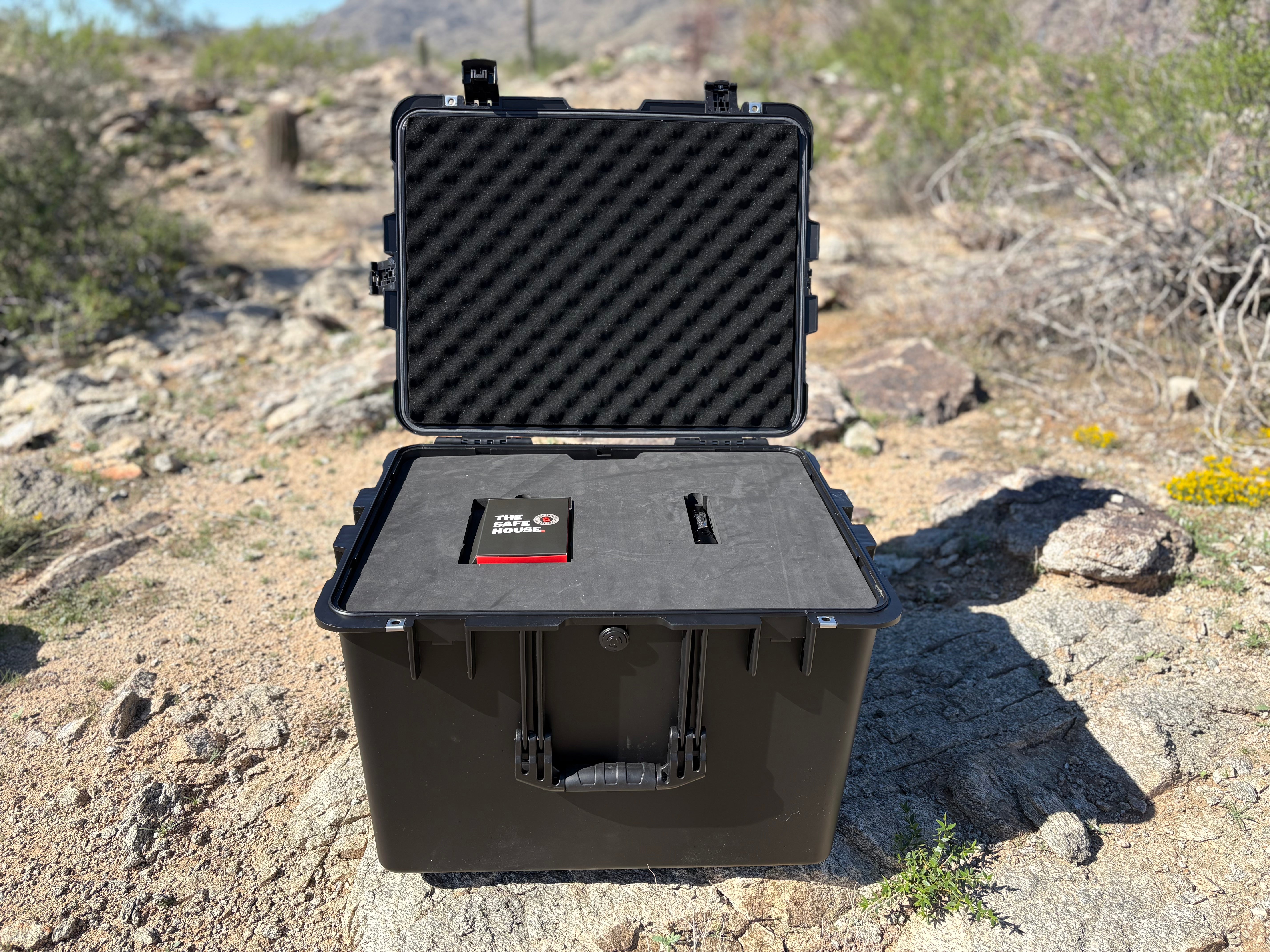Black hard-shell protective case with foam interior on a rocky desert landscape